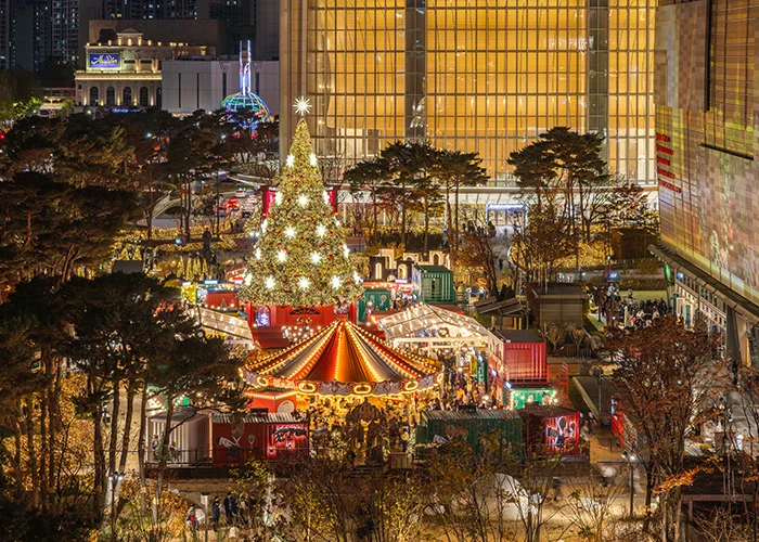 제2롯데월드몰 입구의 모습입니다. 유리 문이 6개가 있고 위에 롯데월드몰이라는 로고가 있습니다. 한 사람이 들어가고 있습니다.