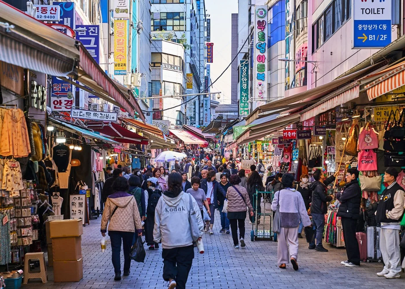 남대문 시장의 먹거리 골목 풍경, 길 양옆으로는 먹거리 상점들이 다닥다닥 붙어있고, 천장 가운데에는 국밥 종류의 전광판이 걸려있다.